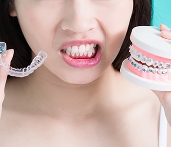 Woman comparing clear aligners and metal braces