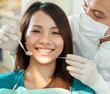 Happy female patient getting her teeth examined