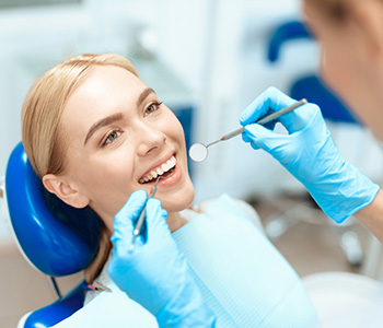 Happy young woman getting her teeth examined