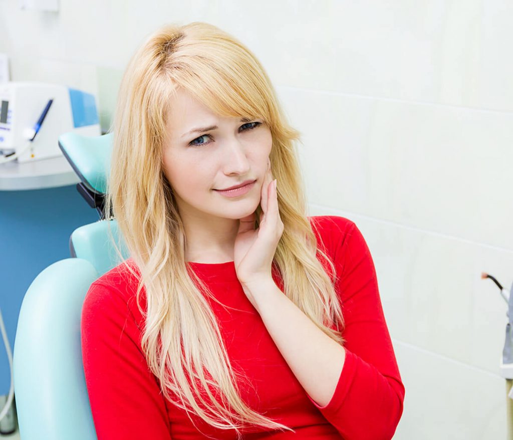 Young woman holding her cheek in pain