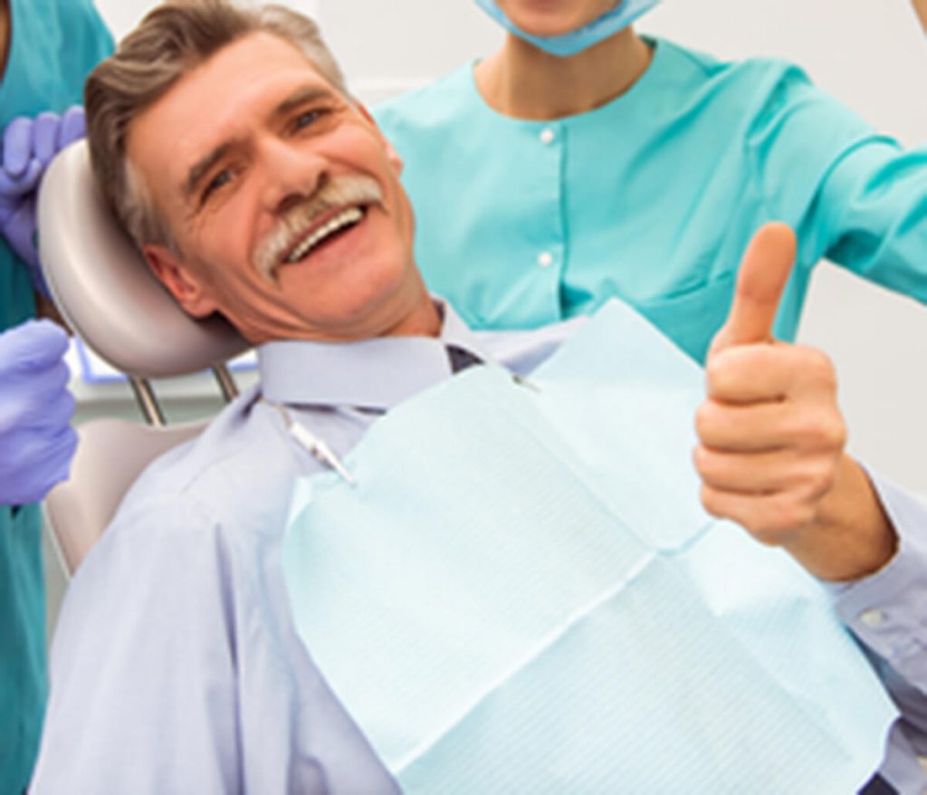 Middle-aged male patient smiling and giving a thumbs up